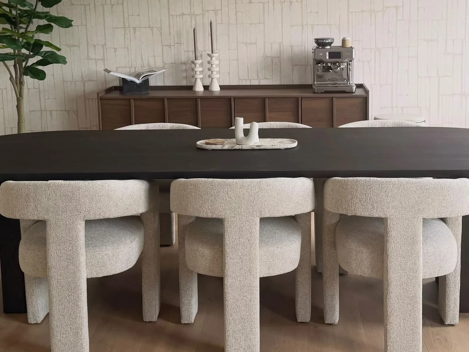 De studio in Haarlem, met houten vloer, een donkere eettafel en bouclé-stoelen